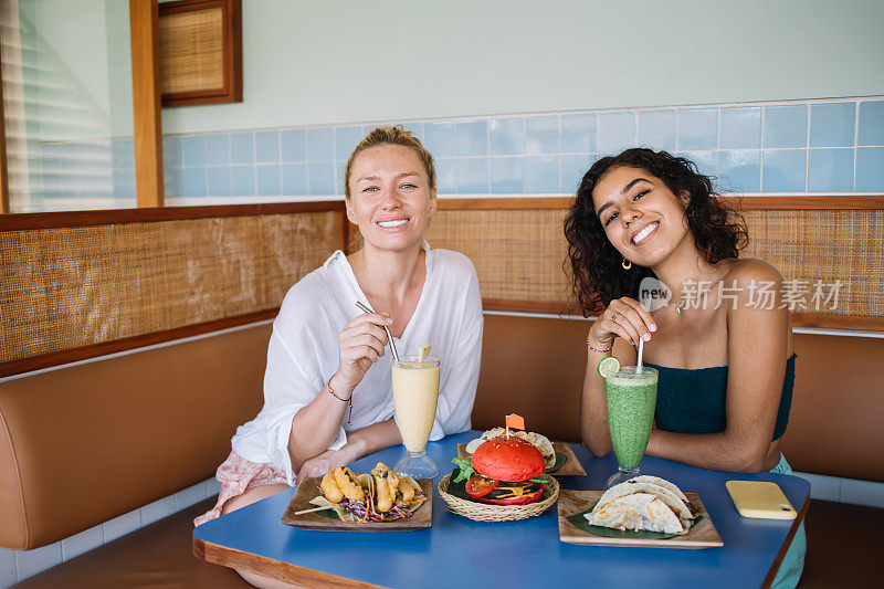 快乐的多种族最好的朋友的肖像微笑在相机在积极的会议分裂墨西哥午餐，有趣的女性顾客享受tex mex食物在消遣品尝拉丁美食